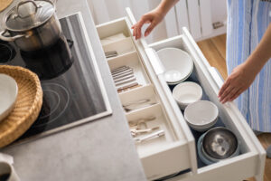 A pair of hands open two well organized kitchen drawers.